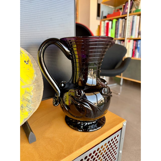 This hand-blown black amethyst glass water pitcher was crafted in 2005 by master glassblower Garrett Vilicich for Liberty...