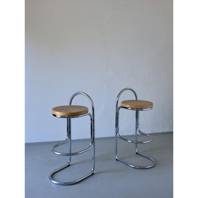 A set of two vintage bar stools featuring tubular chrome frames and round cane seats. Condition: good vintage condition...