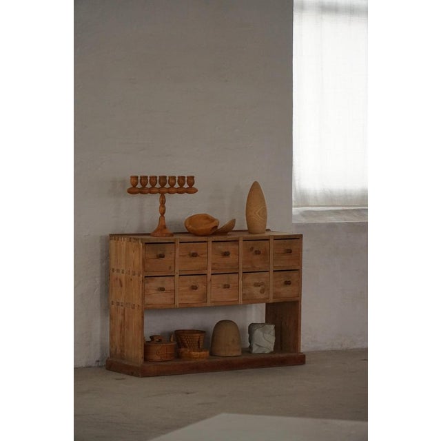 A distinctive 19th-century Scandinavian apothecary-style cabinet, crafted in solid pine with a rich rustic character. The...