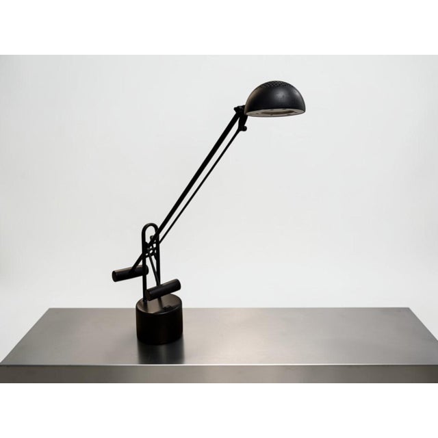 Vintage black counterbalance desk lamp featuring a long adjustable arm, cylindrical counterweights, and a rounded metal...