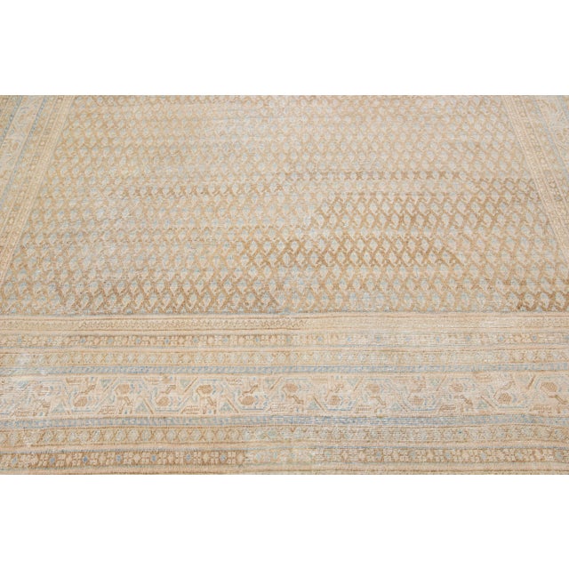 This exquisite antique Hamadan rug is hand knotted from premium wool, boasting a beige field complemented by a...
