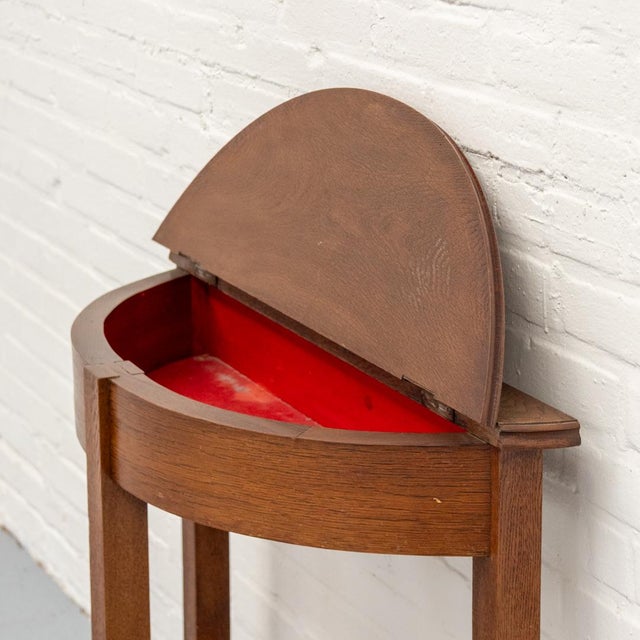 Semi-circular oak storage table from the 1930s-1950s, featuring a hinged top that opens to a spacious storage compartment....