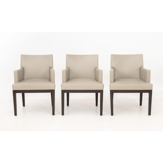 Set of Six Christian Liaigre Style Dining Armchairs, with taupe upholstery on wood legs. 33" H x 24.5" W x 25" D; seat:...