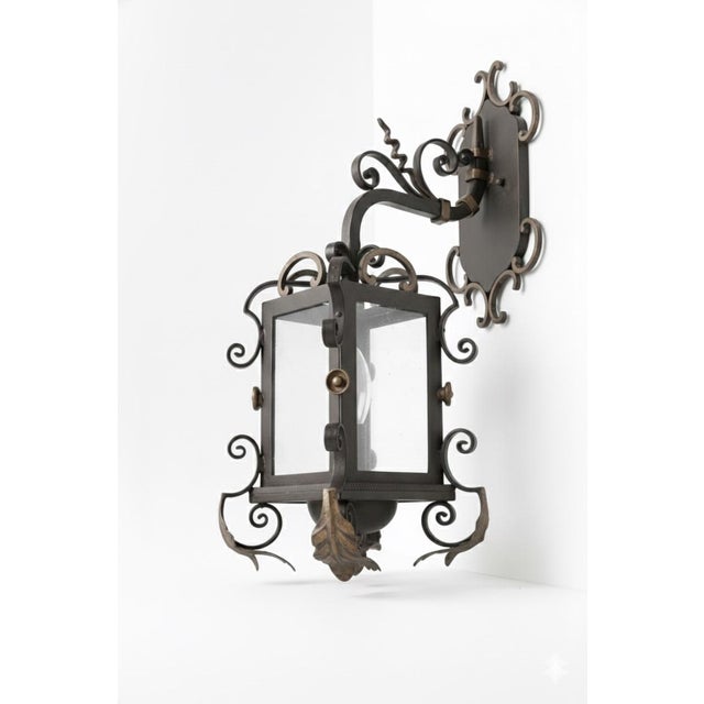 Crafted from heavy-gauge hand-forged wrought iron, this sconce features a dramatic architectural silhouette characterized...