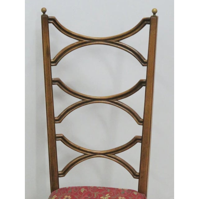 Brass finials. Upholstered seat. Carved frame with gilt highlights.
