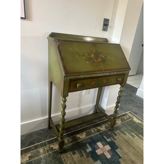Charming vintage secretary desk in a beautifully aged olive green finish, adorned with hand-painted floral bouquets on...