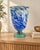 Flowing cobalt-blue and milky-white swirls give this footed glass vase a striking sense of movement. The elongated body...