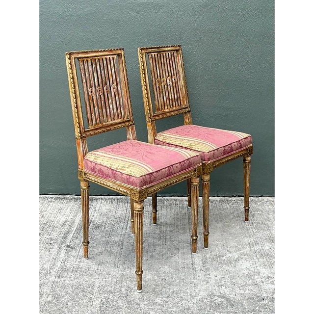 Crafted in Sweden, this elegant pair of vintage side chairs showcases classic Gustavian and Neoclassical design...