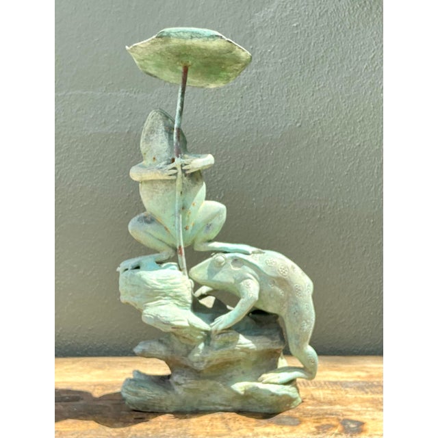 This captivating vintage garden sculpture features two playfully rendered frogs perched upon a rocky outcrop, one...