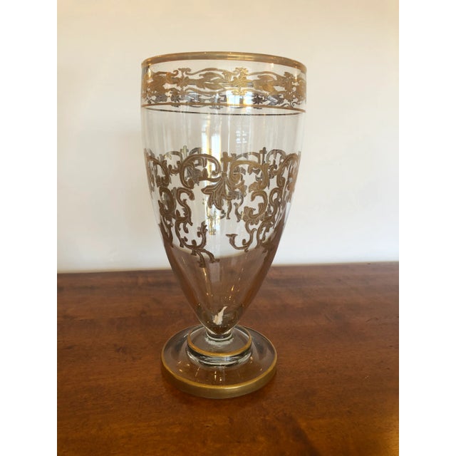 A beautiful medium sized vintage glass vase having ornate gold leaf patterned embellishments.