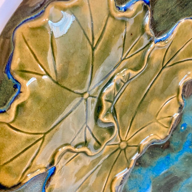 This vintage Global Views glazed earthenware ceramic decorative plate features two frogs perched and jumping from lily...