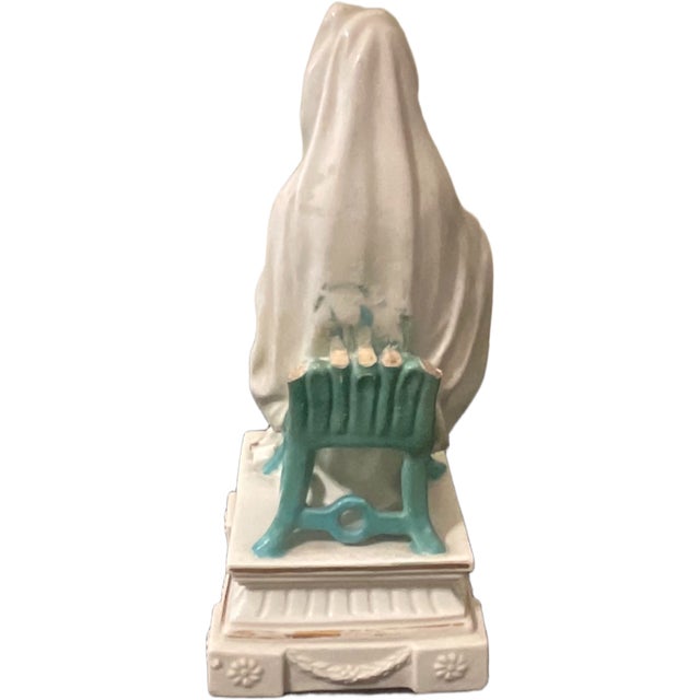 This elegant 19th century porcelain figurine depicts a seated Madonna cradling the Christ Child, blending religious...