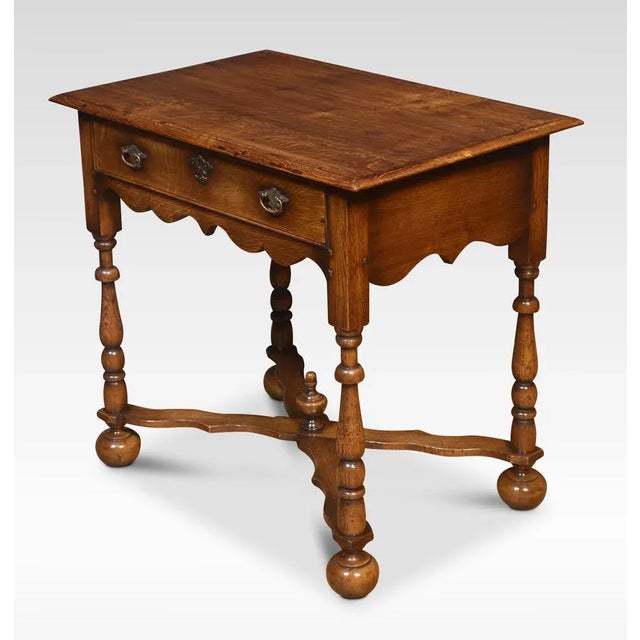 Oak side table. the rectangular top with moulded edge above a large single oak frieze drawer with engraved brass handles....