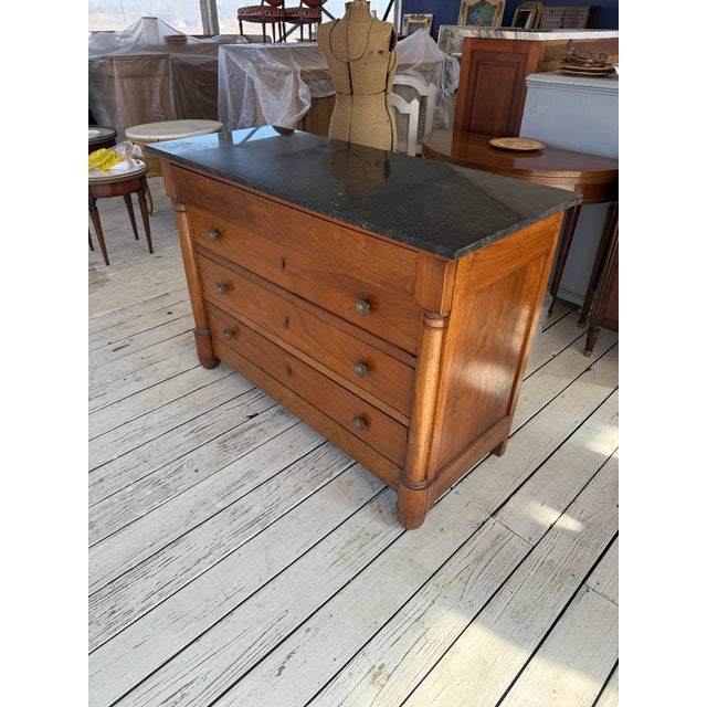 19th Century French Empire Commode from France. Made of walnut, with a black marble top, the wood has been finished with a...