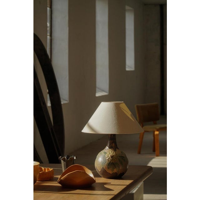 Decorative Danish ceramic table lamp from the 1970s, featuring a hand-crafted floral motif with sunflowers and leaves in...