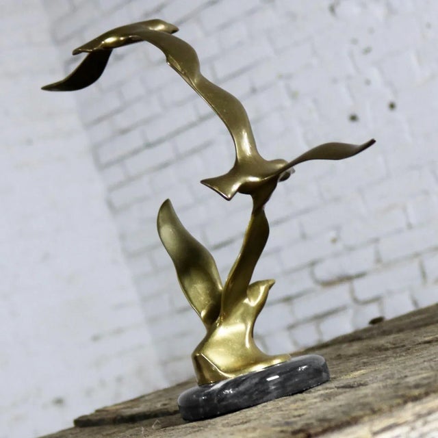 Mid-century modern three birds in flight brass sculpture on a round black marble base in the style of C. Jere; however,...