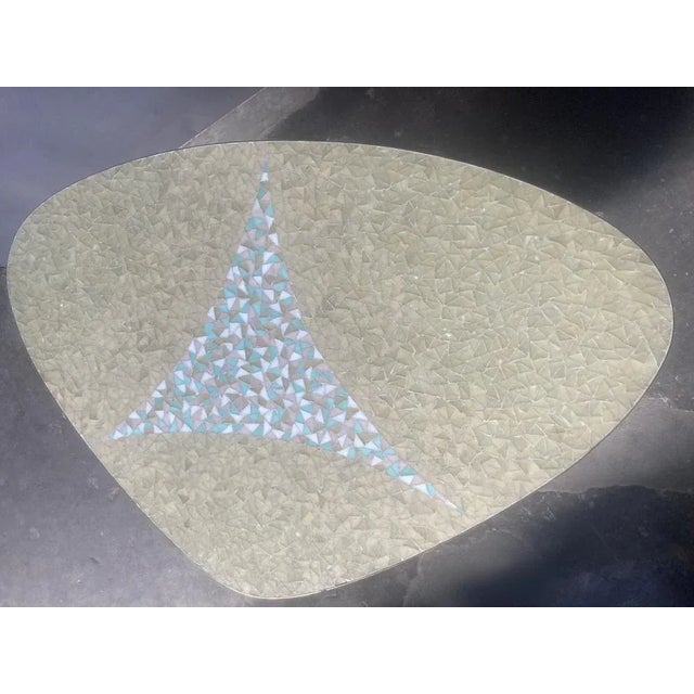 Eccentric mosaic covered coffee table, in a rounded-off triangular shape, white, sand and green colored shards, and wooded...