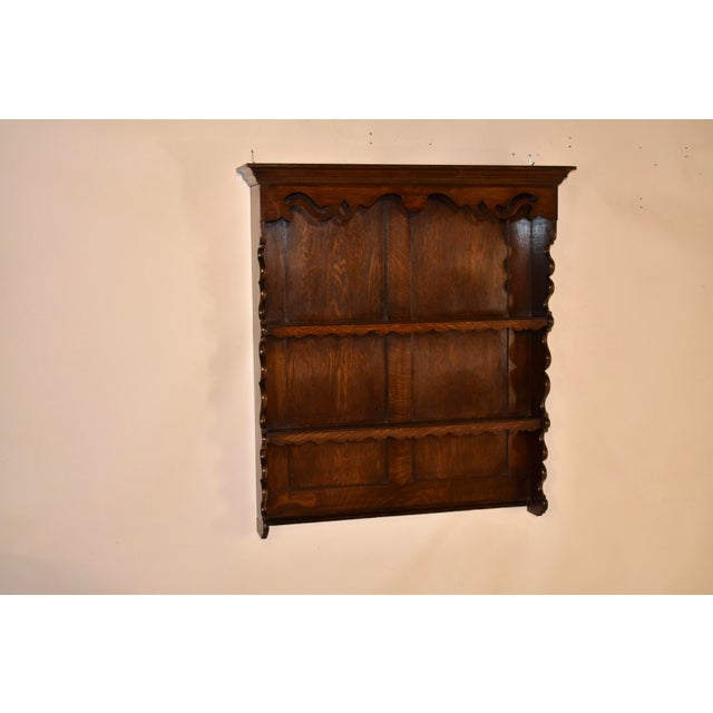 Late 19th century oak hanging wall shelf from England. On the top of the shelf sits a lovely crown molding, following down...