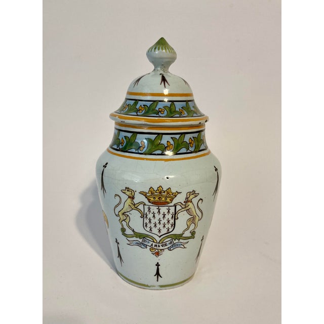 A rare Desvres French faience lidded jar in the style of Quimper Porquier Beau. It features a Breton playing a biniou...