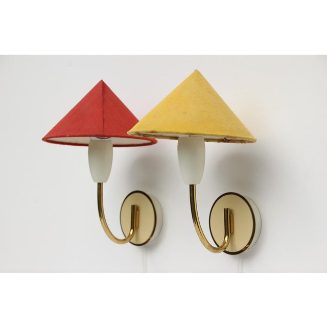 A pair of wall lamps from the mid-20th century with red and yellow fabric shades. Made in Germany in the 1950s. Metal...