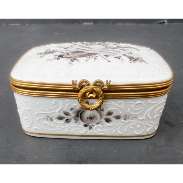 Fine porcelain hinged-lid box with a mandolin and music on the lid. Raised scrolling pattern and gilt rim. Hallmarked...