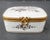 Fine porcelain hinged-lid box with a mandolin and music on the lid. Raised scrolling pattern and gilt rim. Hallmarked...