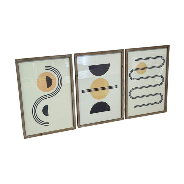 Set of three coordinating geometric abstract art prints featuring black and muted gold-toned forms on light backgrounds....
