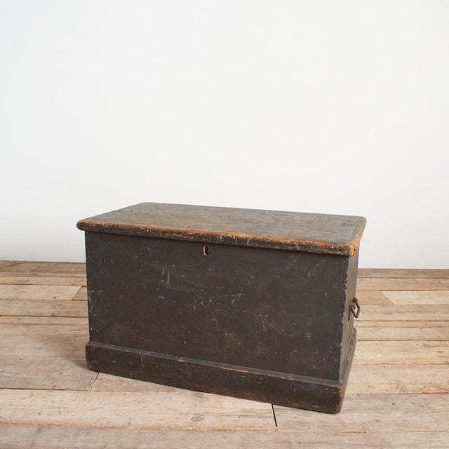 An original antique wooden pine chest originally used as a Victorian travel trunk. The trunk has a black finish and...