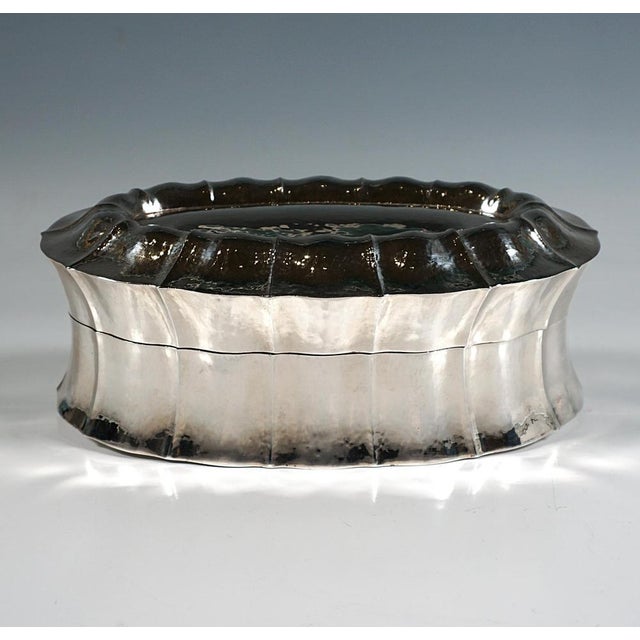 Oval lidded box made of hammered and embossed silver, rim of the lid domed and pleated, the fine pleats continuing down...