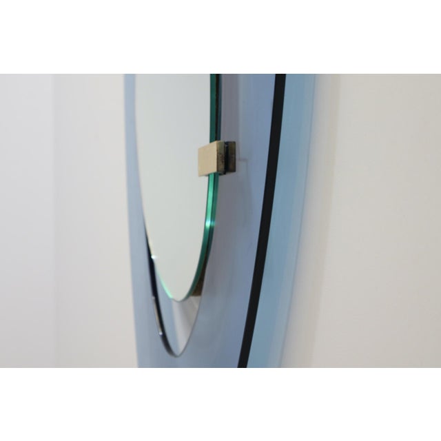A mirror by Max Ingrand for Fontana Arte, 1950, with an asymmetrical shape in blue glass and brass joints. Franco Deboni,...