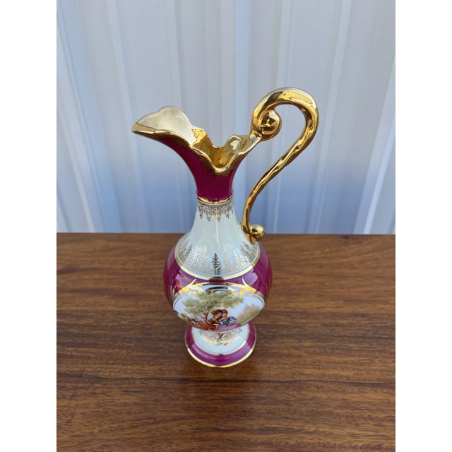 Porcelain petite decorative ewer made in Limoges, France. Elegant gilt handle and mouth with deep burgundy body and a...