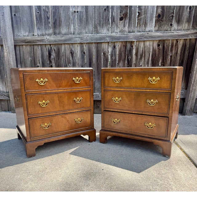 Three drawer bedside chests in the Chippendale style made by Henredon circa 1970's. Made with walnut veneers and brass...