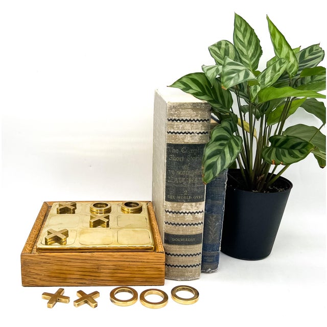 A charming and well-made tic-tac-toe set featuring a warm wood box with a fitted brass game board that rests neatly into...