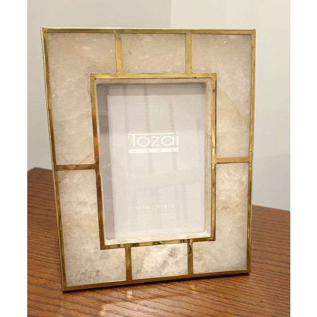 Contemporary solid stone quartz frame is highlighted with fretwork in brass metal. This versatile decorative accent...