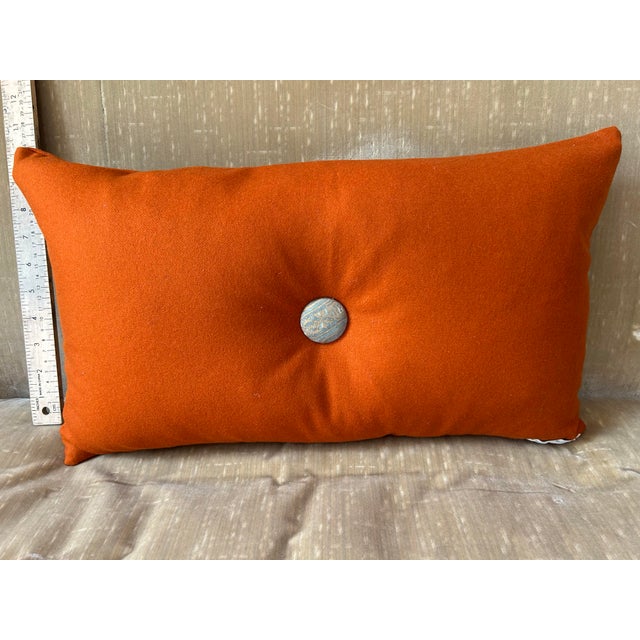 A pillow made with a sumptuous cashmere and embellished with an iconic Fortuny fabric border and button tuft detail.
