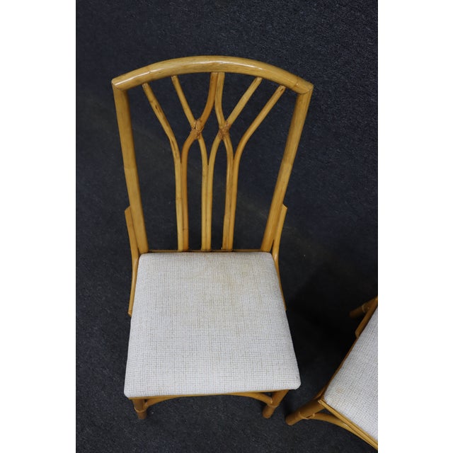 Set of four MCM style bamboo dining chairs featuring sculptural bent bamboo frames with arched stretchers and fan-form...