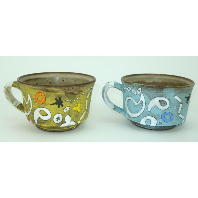 Outta-this-world! A pair of one-eyed alien mugs by Atlanta based Japanese artist, Masa Sasaki. One mug is baby blue and...
