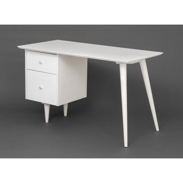 Paul McCobb Style White Painted Wood Desk, the two drawers with gilt porcelain pulls above tapered flaring legs. 29.25" H...