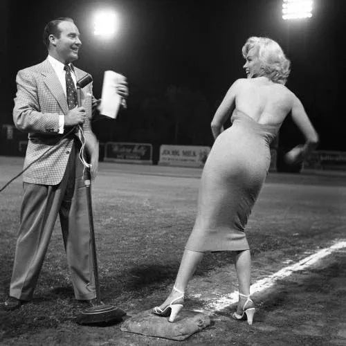 Monroe Throws the First Pitch Marilyn Monroe with Ralph Edwards on a baseball diamond, throwing the first pitch to start a...