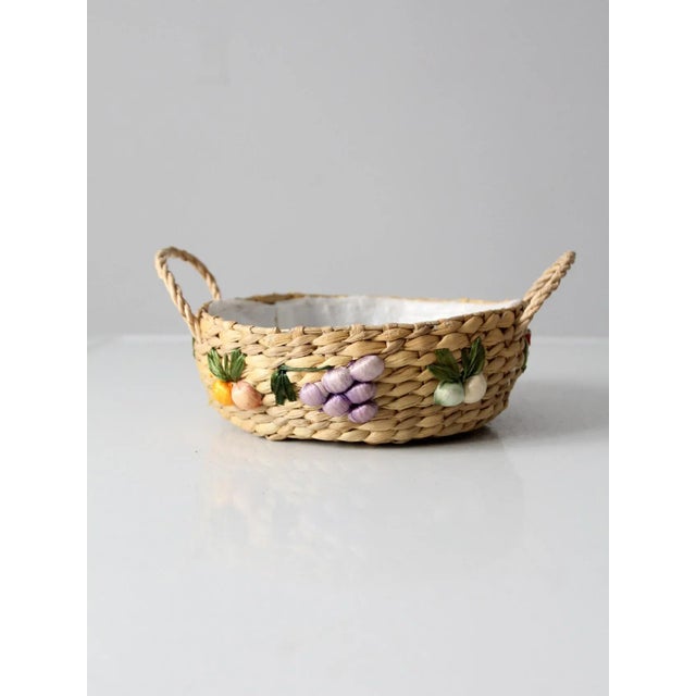 This is a vintage woven bowl circa 1960s. Floral raffia accents decorate the sides of the straw basket. It features a...