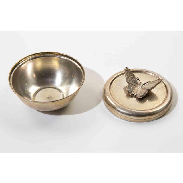 A charming small silver-tone covered bowl featuring an ornate butterfly finial to the lid. The delicately cast butterfly...