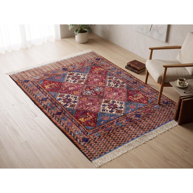 Three ivory diamond medallions patterned in indigo and rust step across the rich berry-red field of this hand-knotted wool...