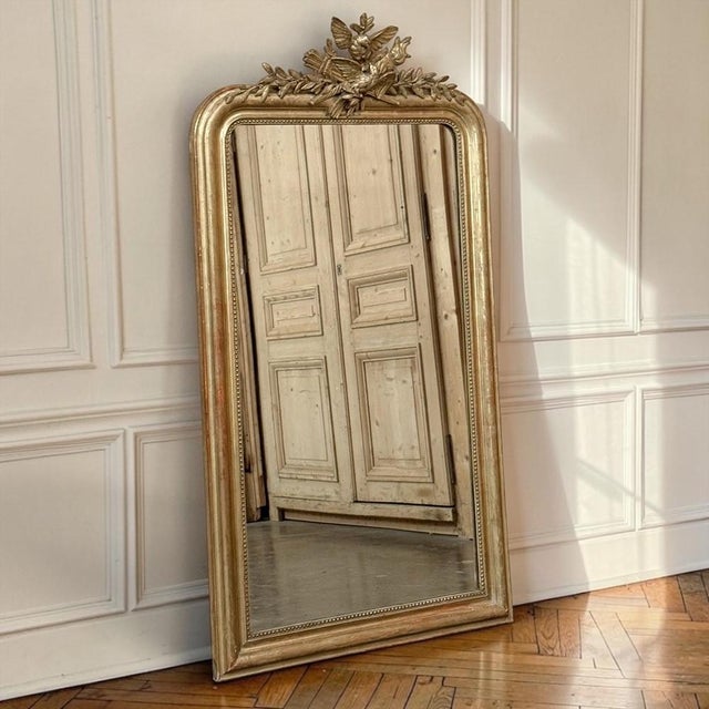 A romantic and beautifully preserved 19th century French antique giltwood mirror in the Louis XVI style, crowned by a...