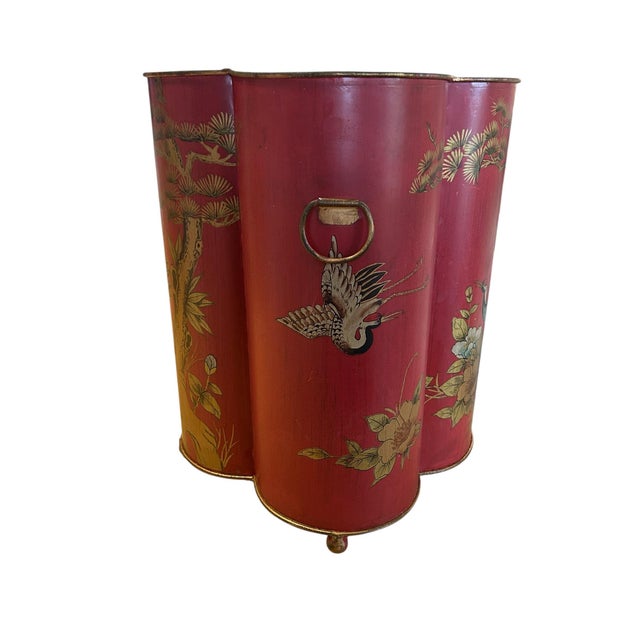 This is a large red tole wastebin in a quatrefoil shape. It is painted with chains and foliage and has two ring handles...