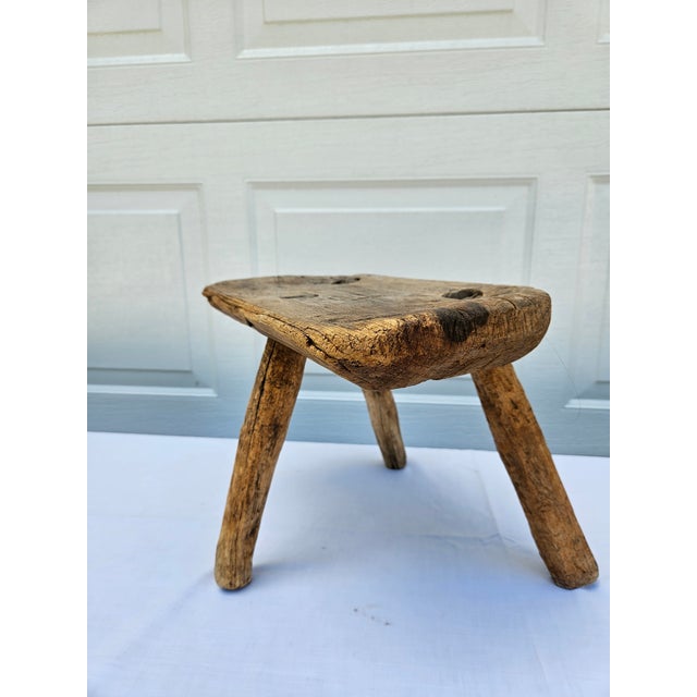 A primitive three-leg milking stool with lots of character. Each leg is pinned in place by an old rusty nail. The stool...