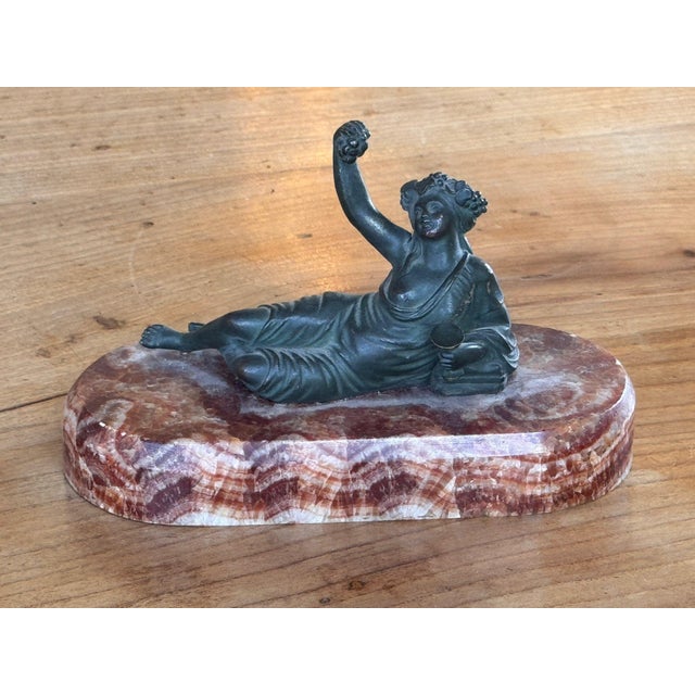 19th century French bronze female figure reclining against a cushion in loose drapery, a wreath of grapes and leaves in...
