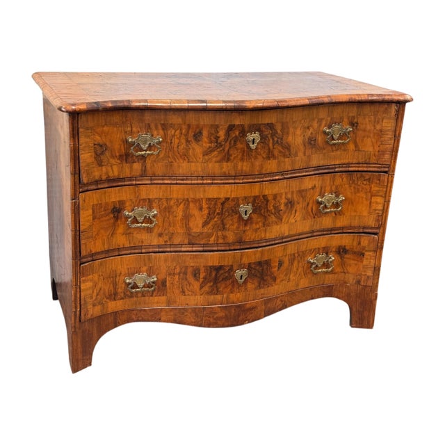 A richly figured burr walnut serpentine commode with crossbanded top and three drawers, all veneered in matched burr...