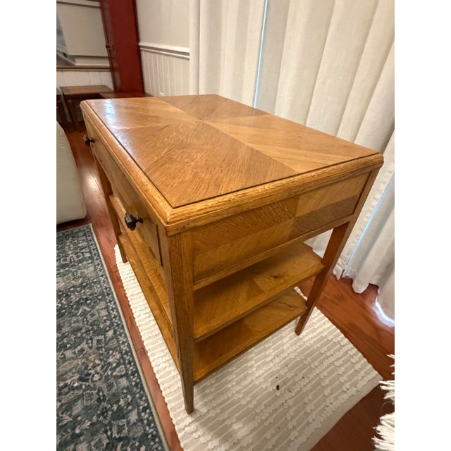 A handsome Theodore Alexander nightstand or side table featuring geometric oak parquetry, warm wood tones, and a...