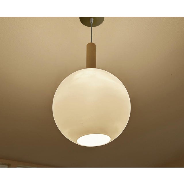 Very large mid century doria pendant light featuring a glass globe shade with a reliefed grid pattern, brass glass cap,...