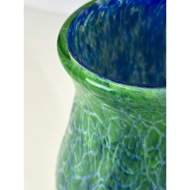 This art glass vase in green and blue crackle glass, attributed to Gunnar Hakansson for Johansfors Glasbruk, was made in...